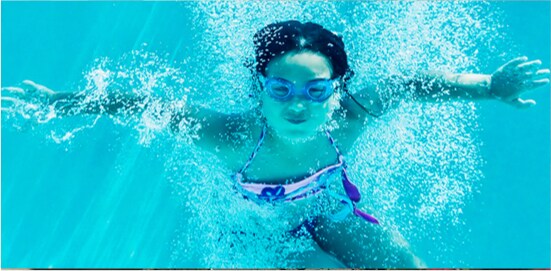A girl wearing goggles who is swimming in a pool.
