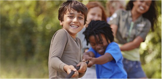 Several children who are pulling on one end of a rope in a game of tug of war.
