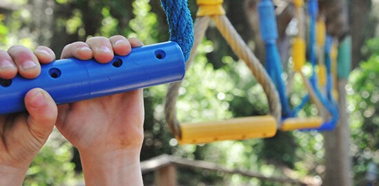 A child hanging from part of a playground.
