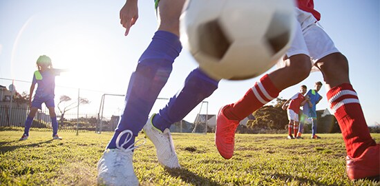 Des enfants qui jouent au soccer sur un terrain de soccer.
