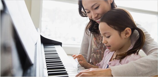 A woman and her daughter at the piano.
