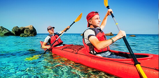 Two young men kayaking in a lake.

