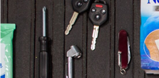 The bed of a truck with a screwdriver, vehicle keys, a tire pressure guage, and a multitool.
