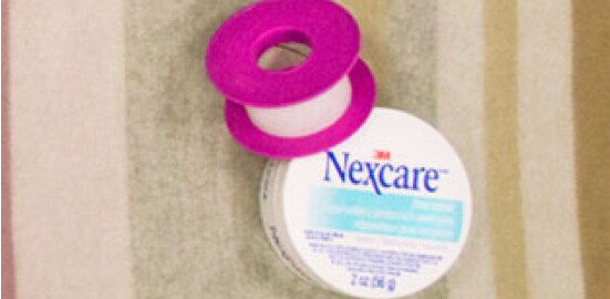 Un contenant du Baume réparateur pour les pieds Nexcare(MC) sur un couvre-lit.
