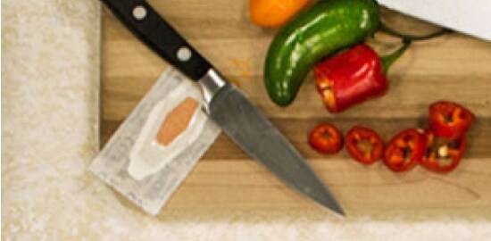 A cutting board with peppers, a knife, and a Nexcare™ Bandage.
