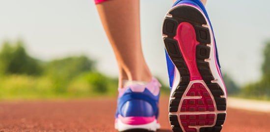 A runner's lower legs and shoes on a running track.
