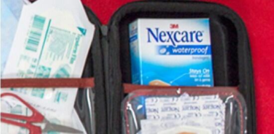 Une trousse de premiers soins pour l’extérieur ouverte dans laquelle se trouve une boîte de Pansements imperméables Nexcare(MC).
